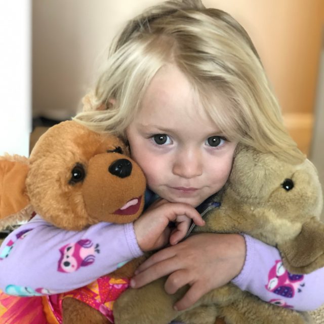 Little blonde girl holding teddy bears