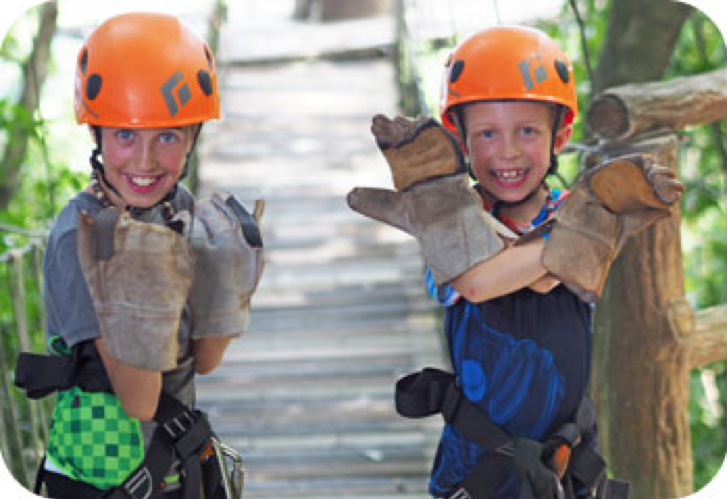 Two kids on a bridge with orange helmets