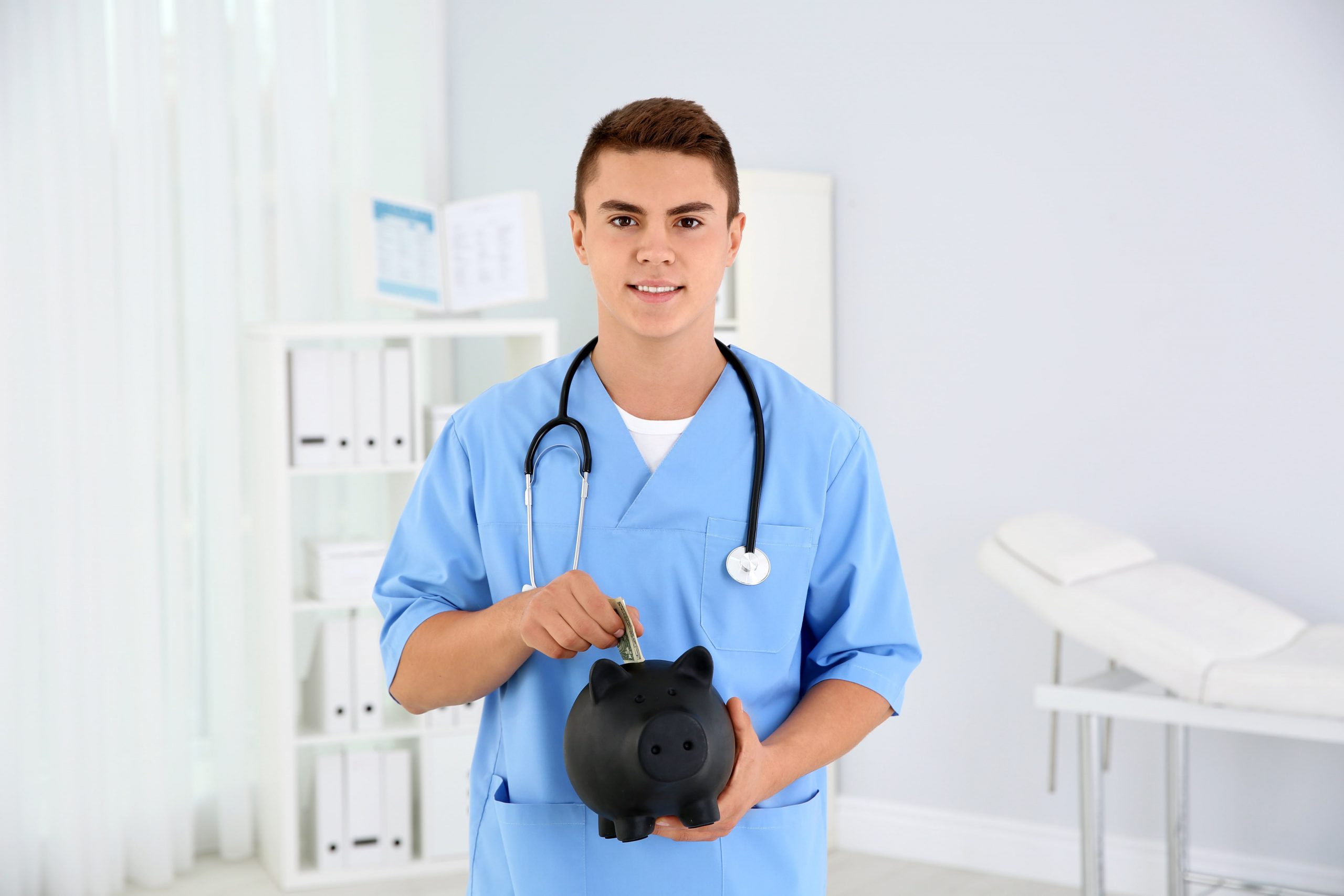 Photo of a medical school student wearing scrubs putting money into a black piggy bank. This image is featured on the Passive Income MD blog, titled "Side Gigs for Pre-med and Medical Students," which originally featured on Physician of Fire