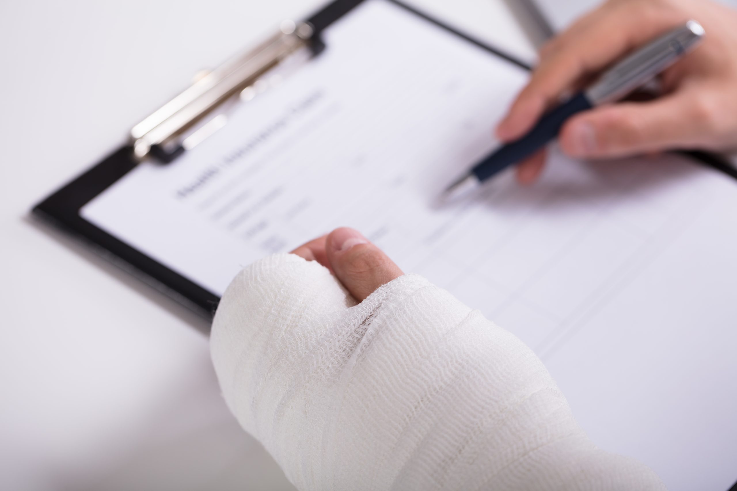 A broken left hand in a cast and a right hand filling out a form. This image is featured on the Passive Income MD blog in a partnership post with Pattern. Get your disability insurance through Pattern, especially if you're a physician. You can get started here: https://www.patternlife.com/quote/physician-disability-insurance-quote-request?uclickid=ebmti5e4b33a3821e8674872457&campid=481226&utm_source=&utm_medium=&utm_campaign=&utm_term=&utm_content=